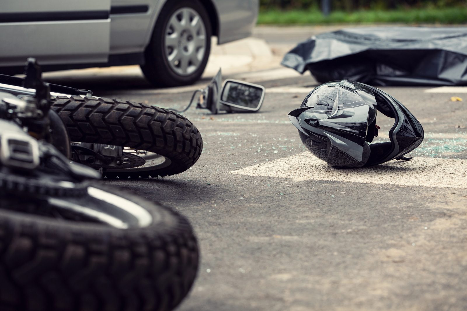 A motorcycle helmet lying in the street after an Atlanta motorcycle crash, with a damaged motorcycle behind it.