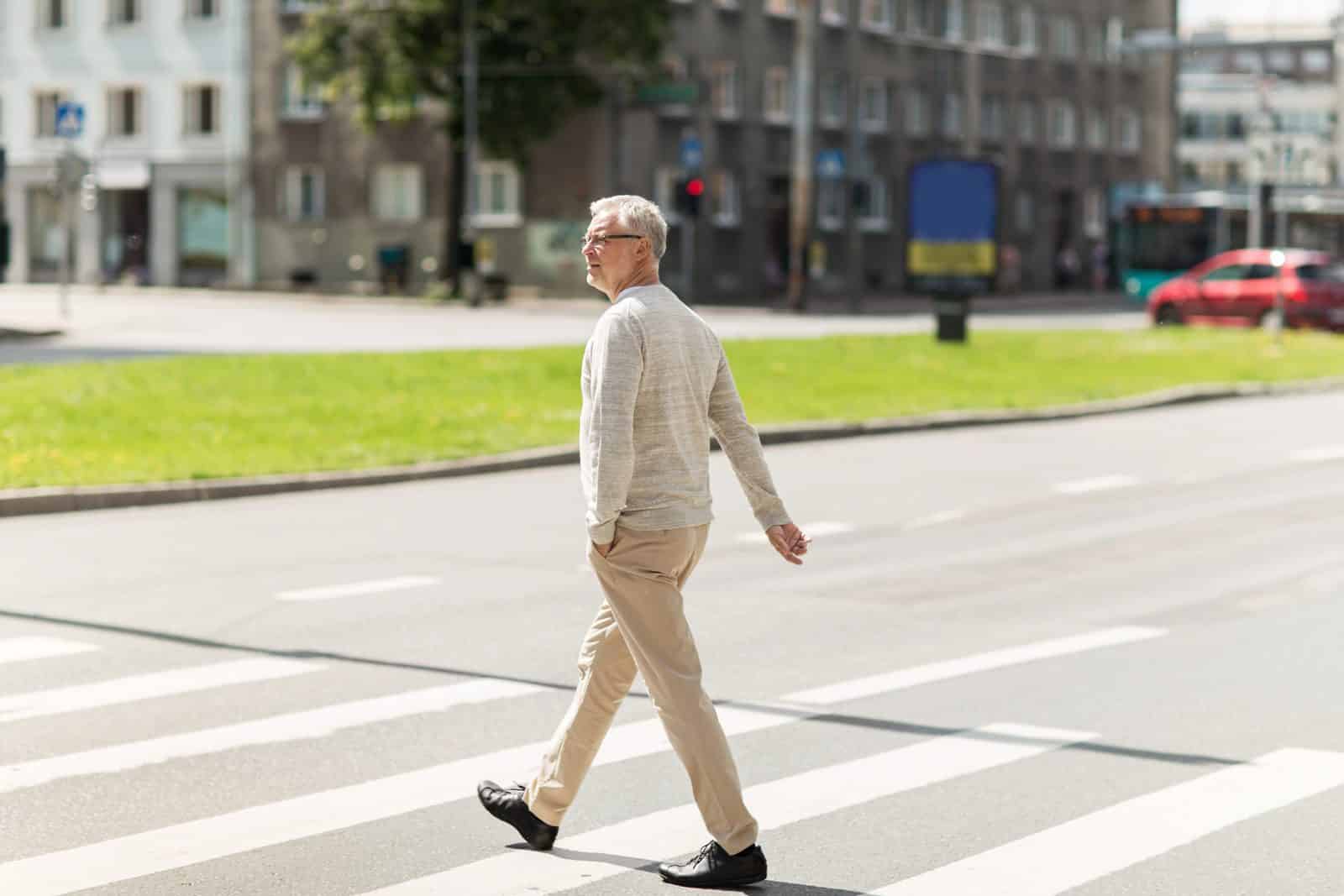 Older man walking across a city crosswalk in Atlanta on a sunny day