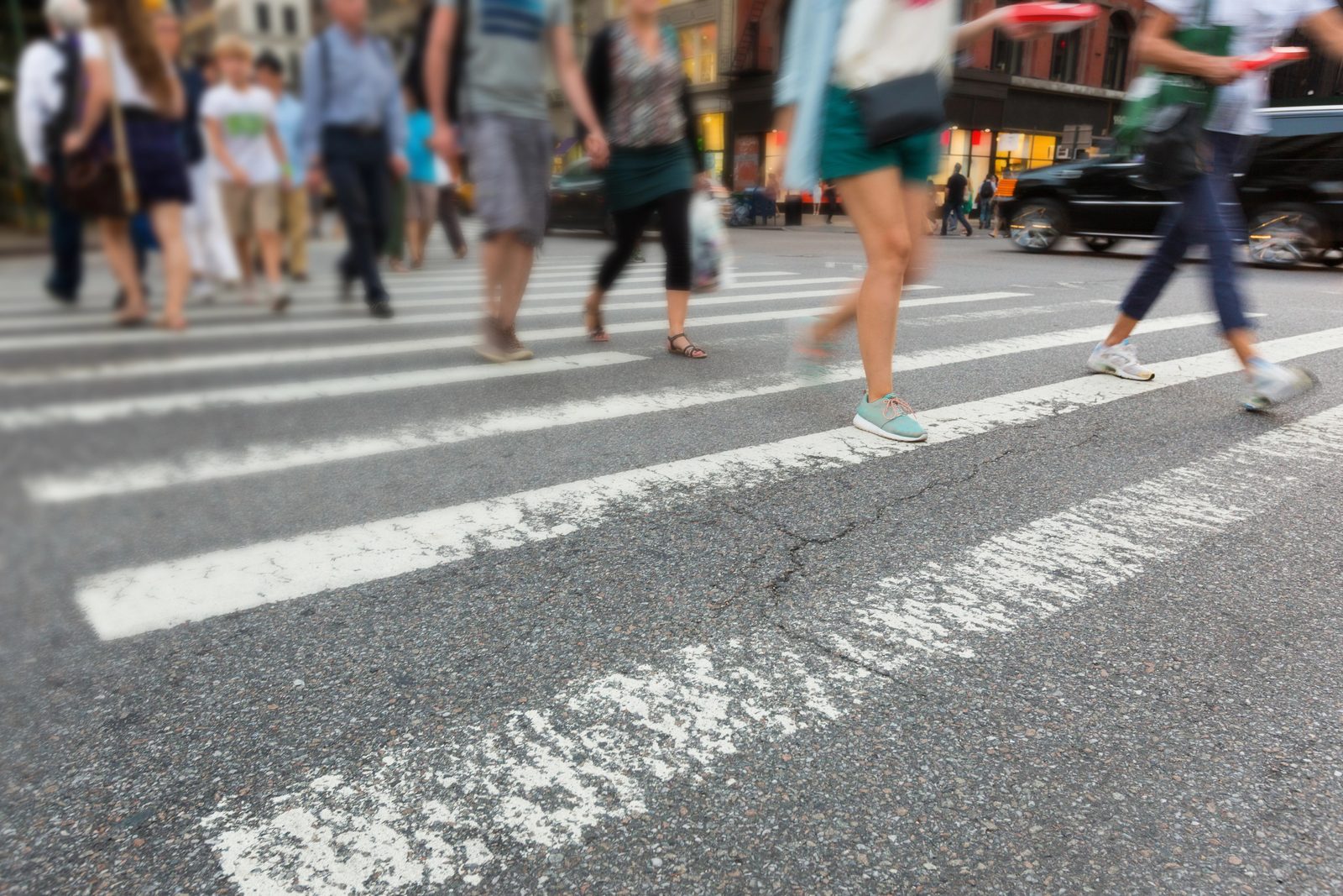 People walking across a zebra crosswalk in a city — Dallas pedestrian accident attorneys.