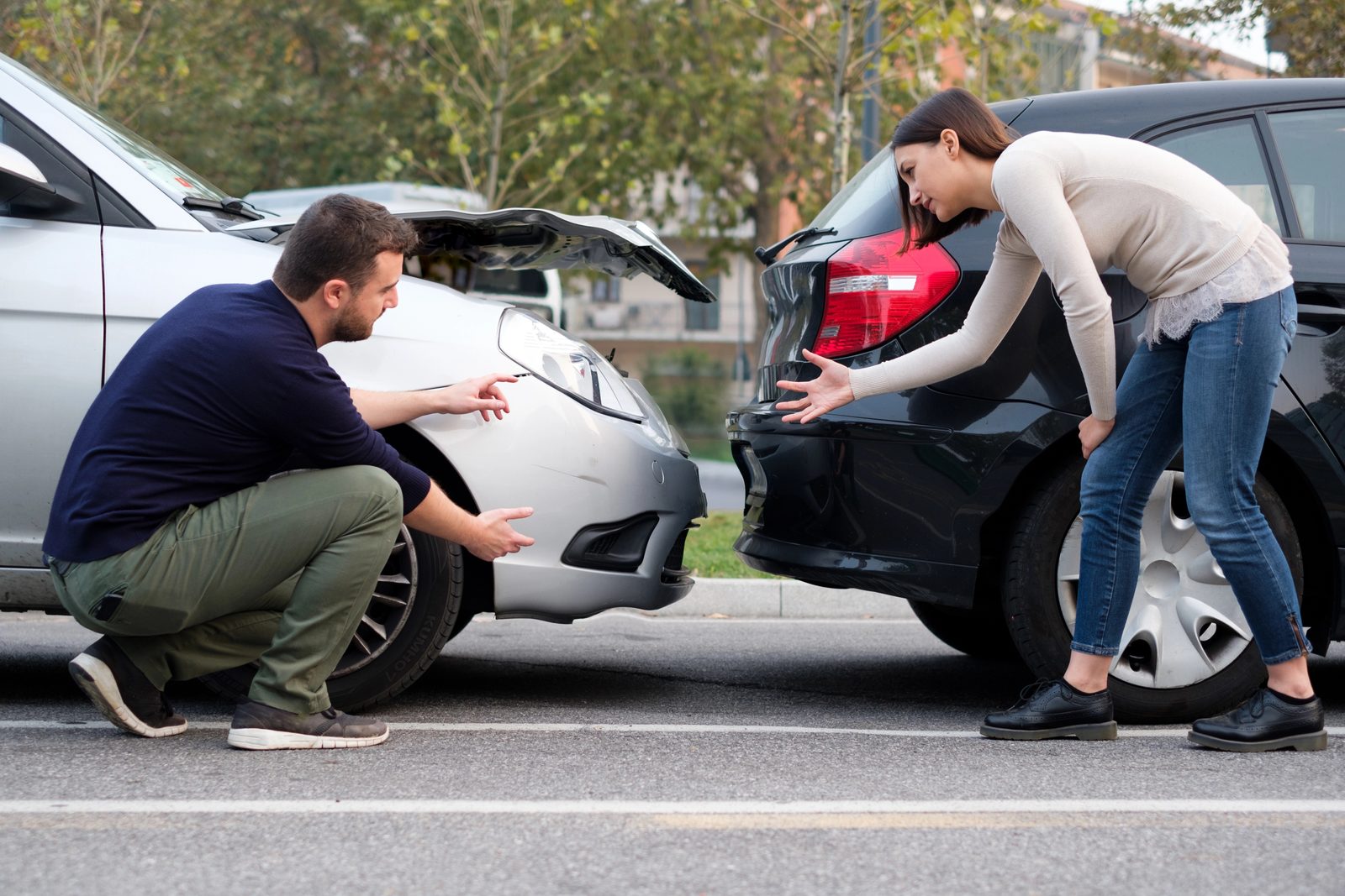 Two drivers inspecting vehicle damage after a rear-end collision in Dallas.