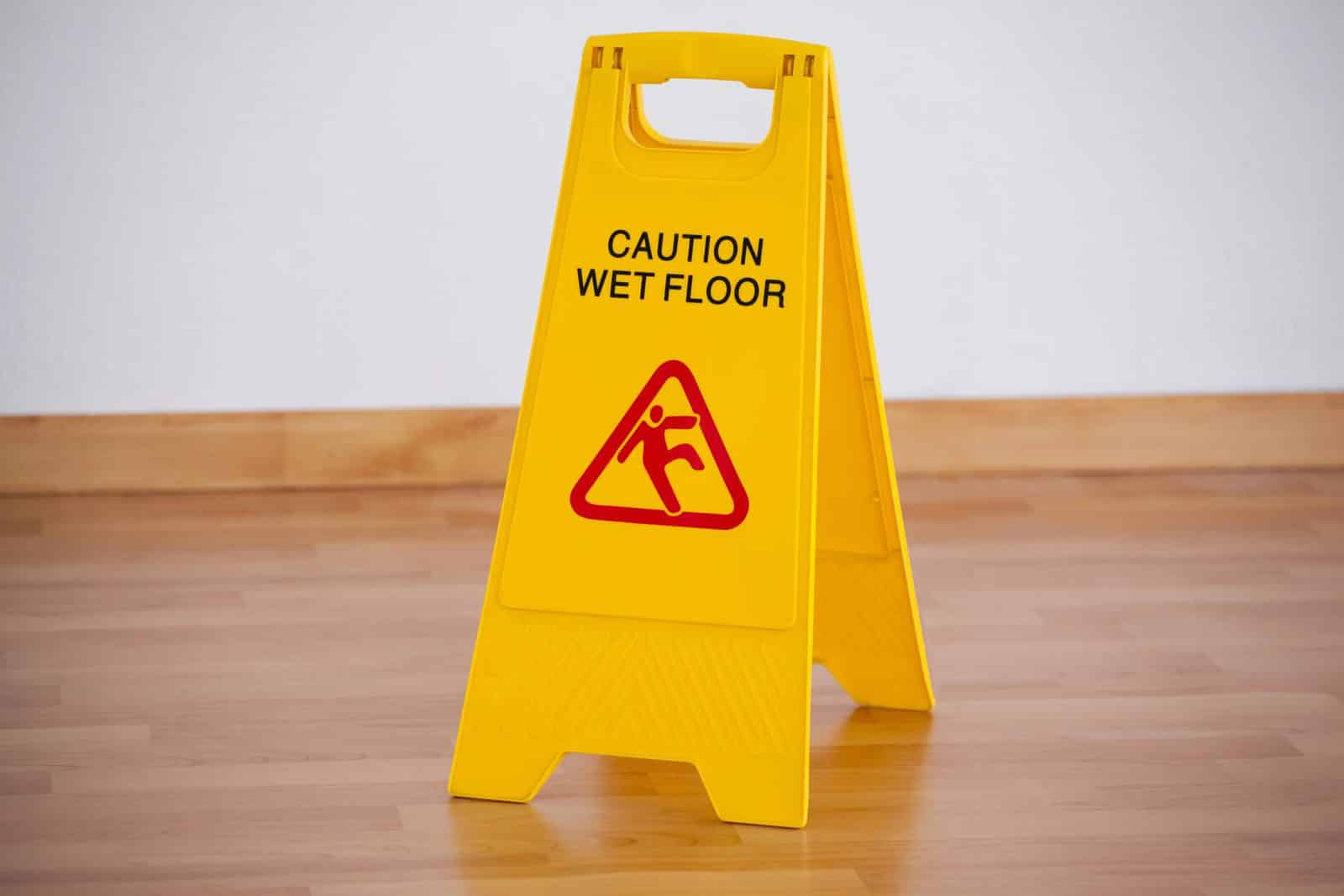 Yellow caution wet floor warning sign standing on a wood floor