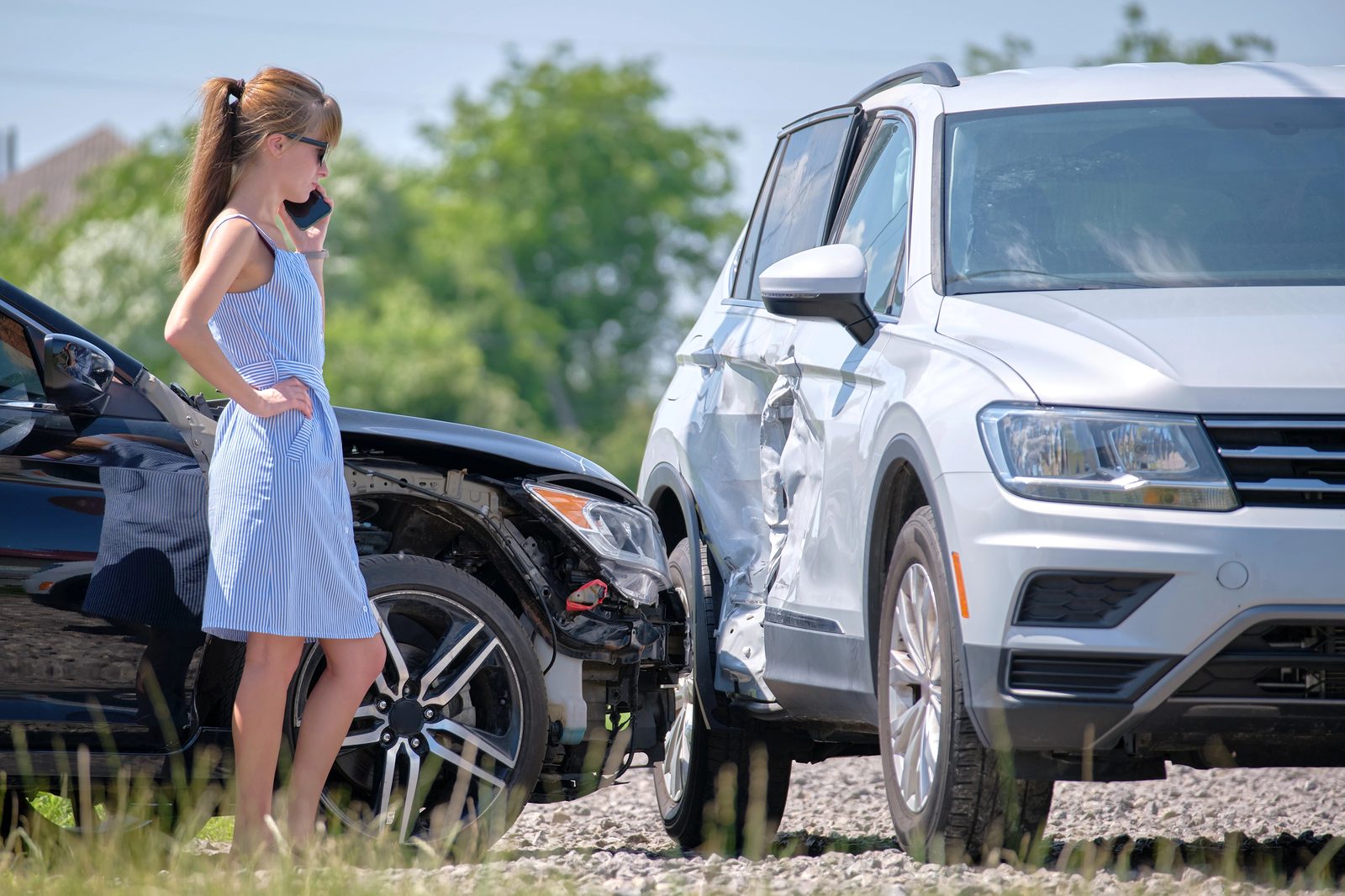 Stressed driver calling for help beside a damaged car after an uninsured-motorist crash near Germantown, Tennessee