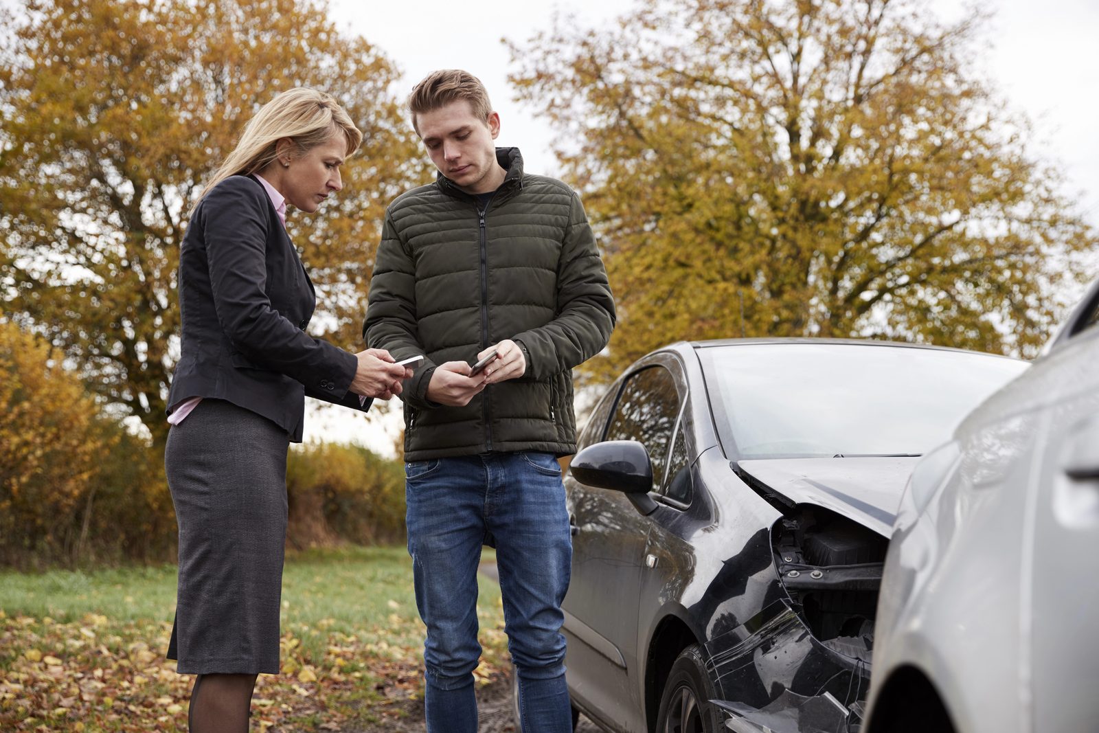 Two drivers exchange insurance information beside a damaged car after a Houston crash with an uninsured or underinsured driver