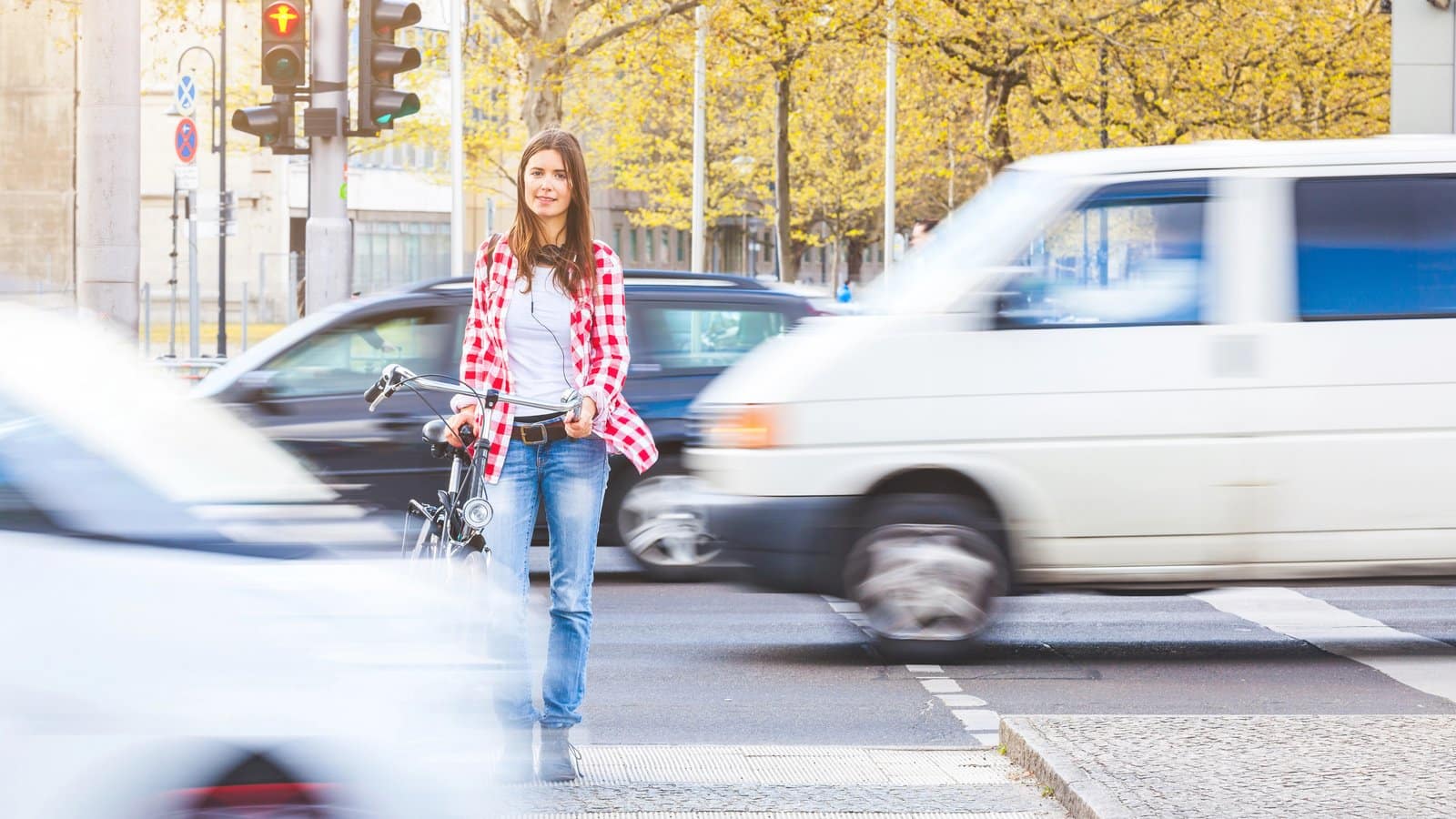 Pedestrian waiting to cross a busy Louisville street as traffic rushes past
