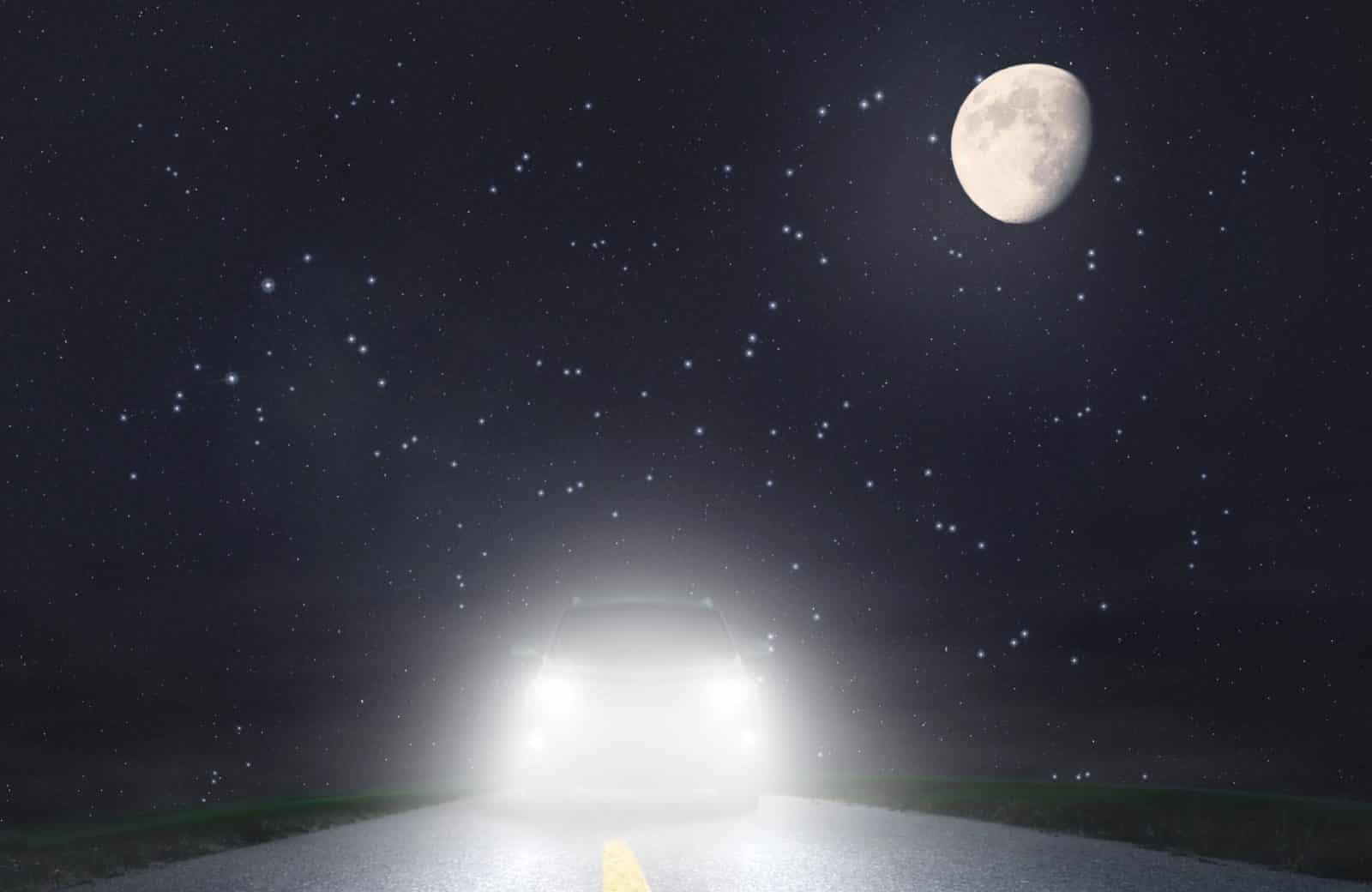A car drives the wrong way toward oncoming traffic at night with headlights glaring, the typical wrong-way crash scenario.