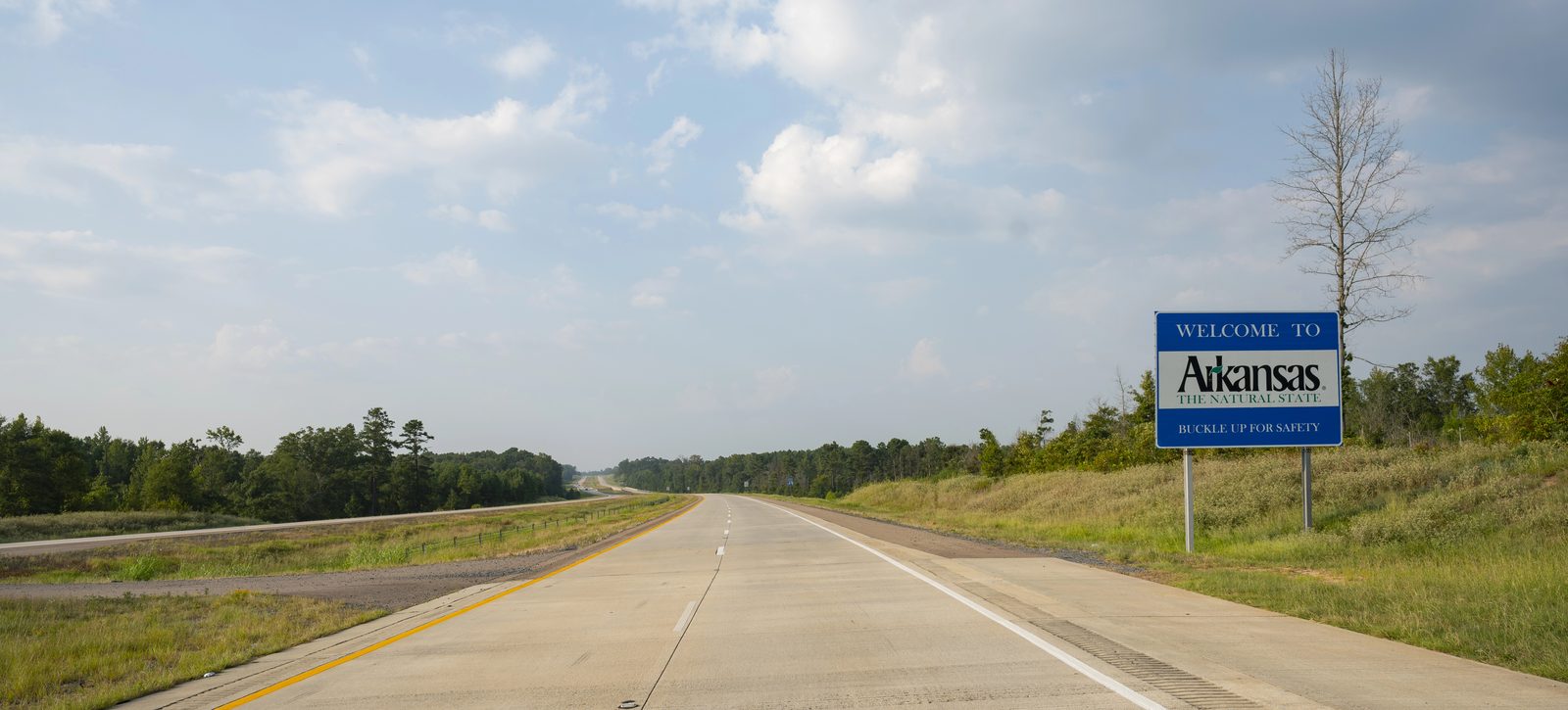 Welcome to Arkansas sign on a divided highway entering the state, the route Jonesboro injury clients travel